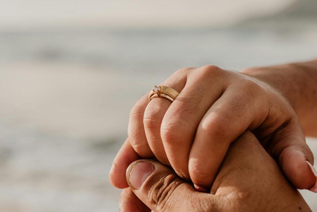 A man holding a woman's hand with a wedding ring